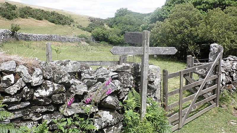 Image of a gate in the countryside, with a sign reading 'public bridleway'. 