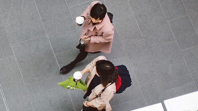 A birds eye view of two students walking with coffee