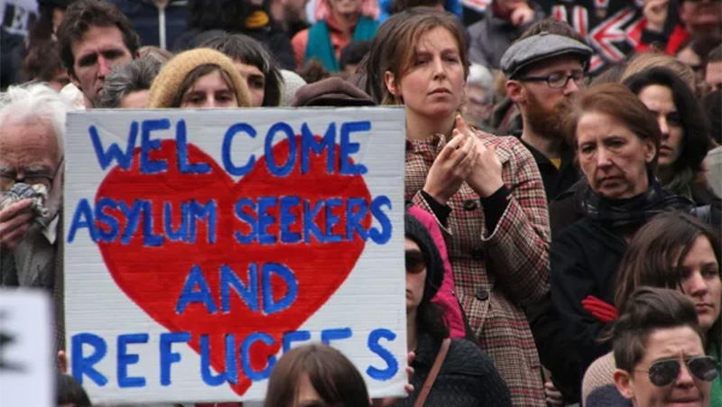 Image of people at a protest, with a banner reading 'welcome asylum seekers and refugees'