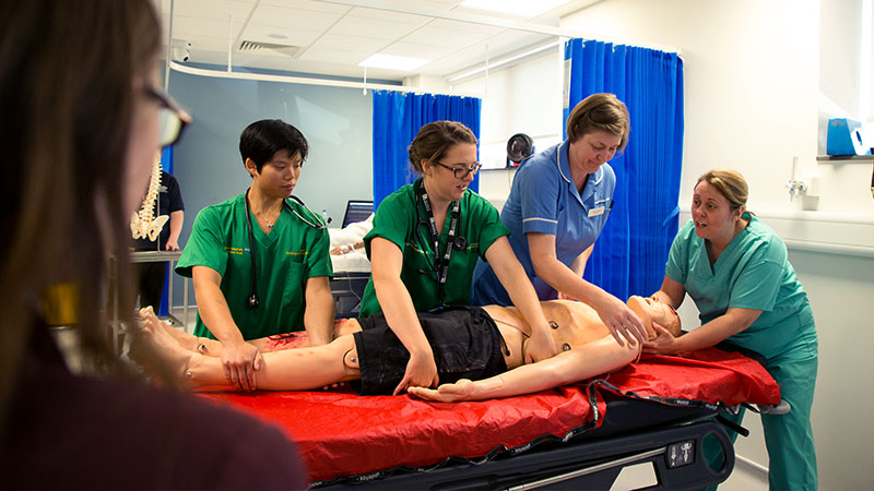 nurse and students practicing procedures on medical practice doll