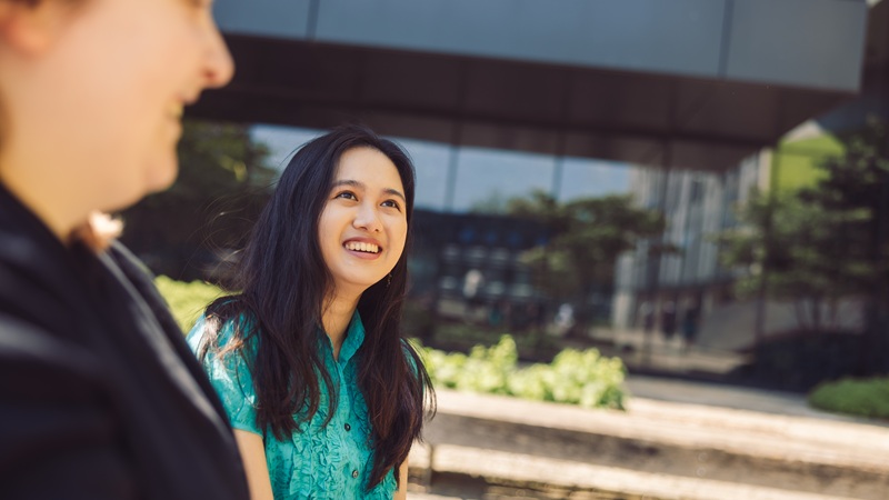 Students outside on campus smiling while talking