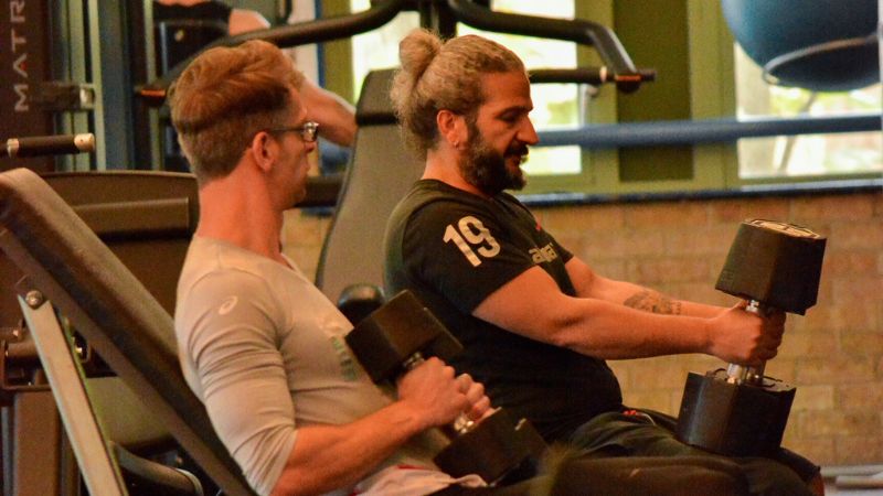 Georg and fellow gym user using dumbbells 