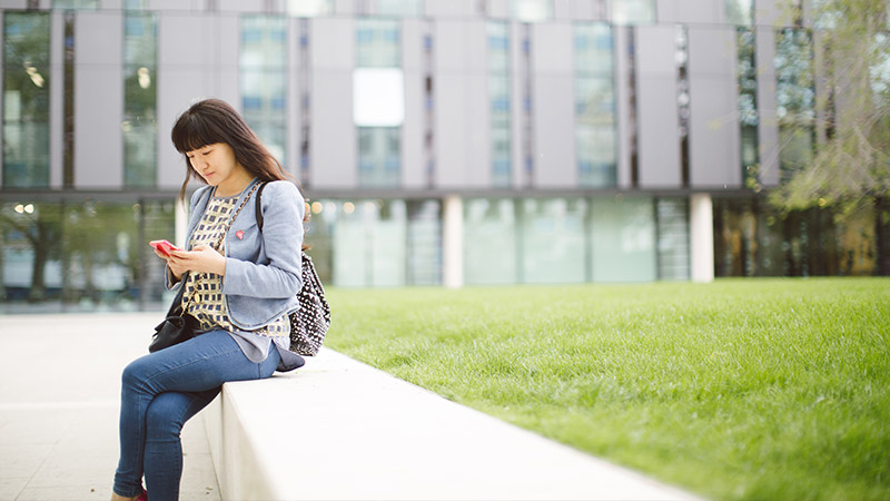 Female student looking at phone in the courtyard