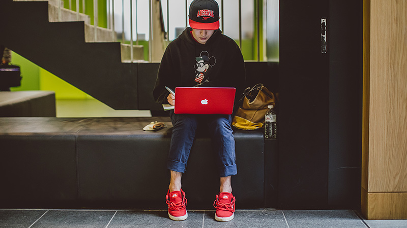 student using laptop and sitting on a bench