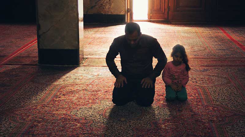 Father and daughter praying in a mosque