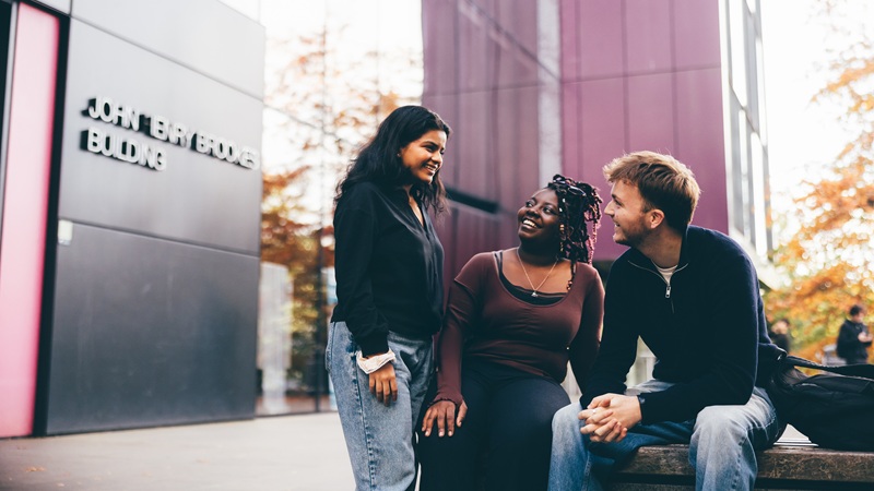 Three students outside on campus having a conversation