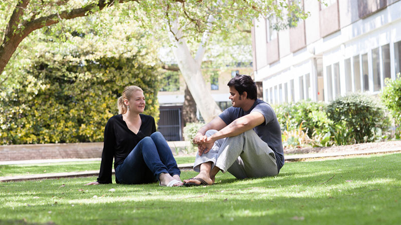 Two students sat on the grass