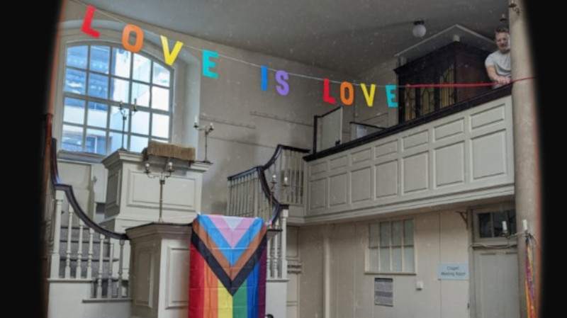 Multicoloured 'Love is Love' banner hanging in church space 