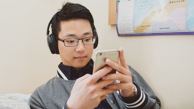 A person wearing headphones and looking at a phone