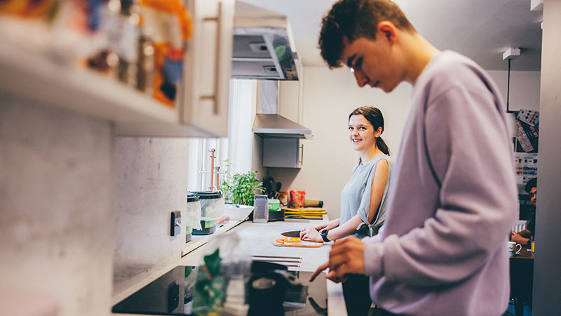 Two students preparing food in a kitchen