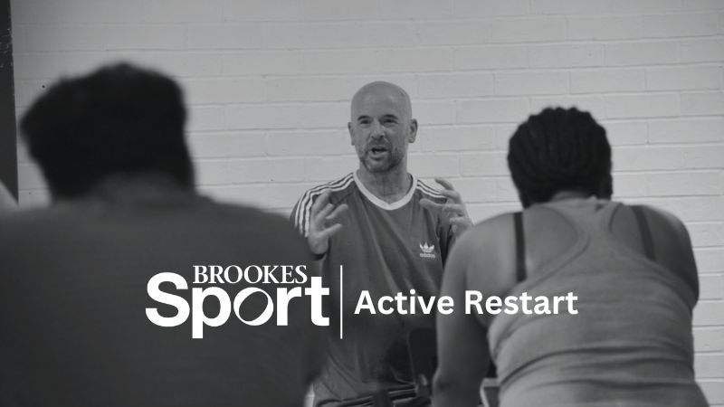Instructor leading spin class with Brookes Sport logo and Active Restart written over the top