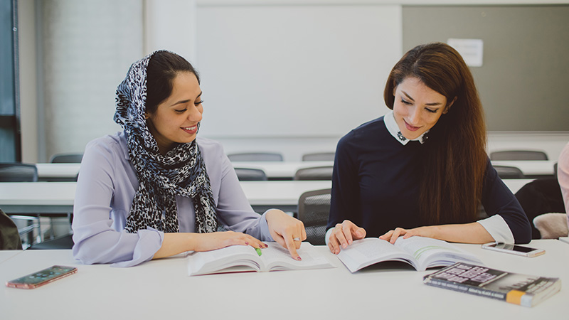 Two female students studying together in classroom