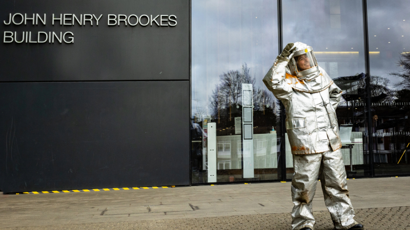 A person in an astronaut suit outside Oxford Brookes University