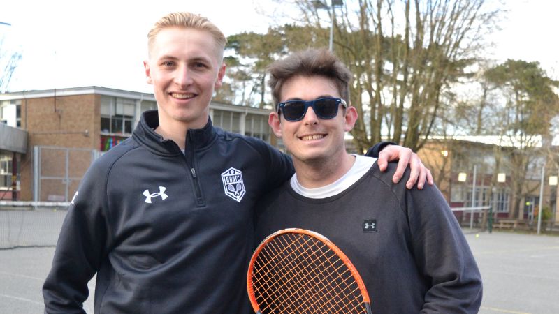 Two tennis students smiling at camera