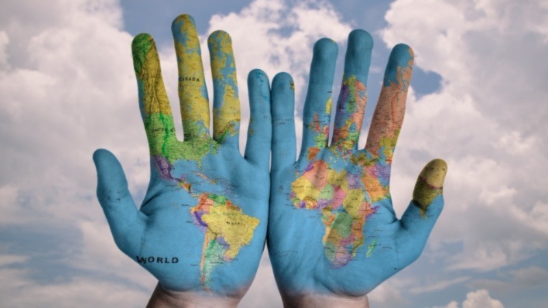 a pair of hands side by side with the map of the world painted on the open palms