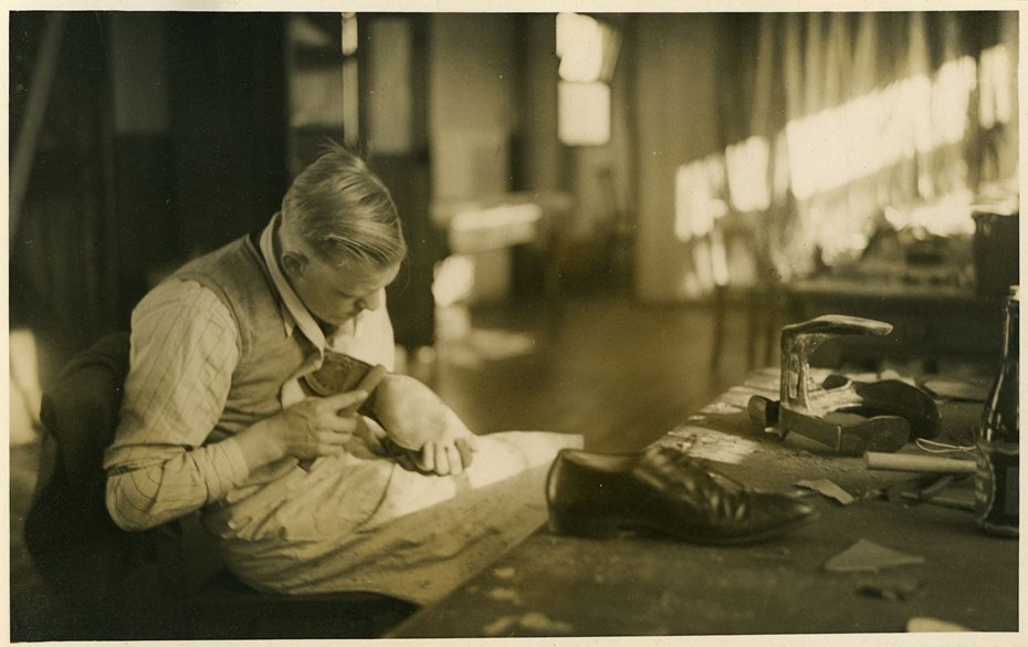 Sepia photograph of a man making a shoe.