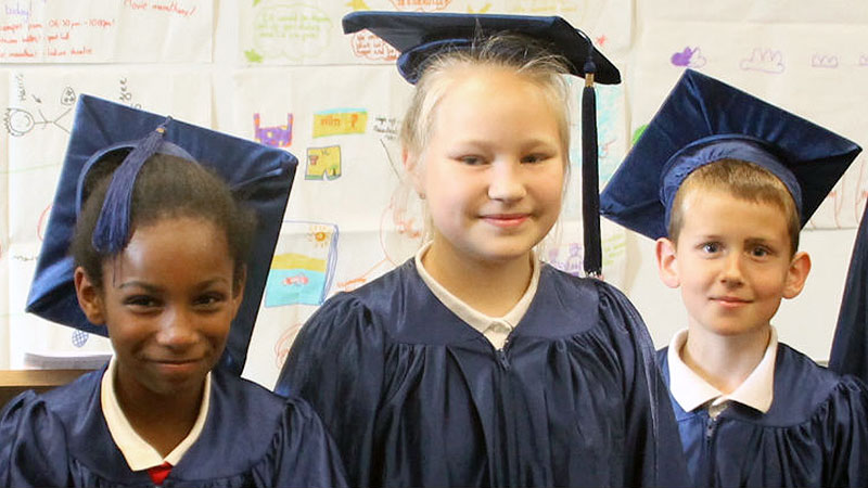 Three young children with wearing graduation cap and gowns