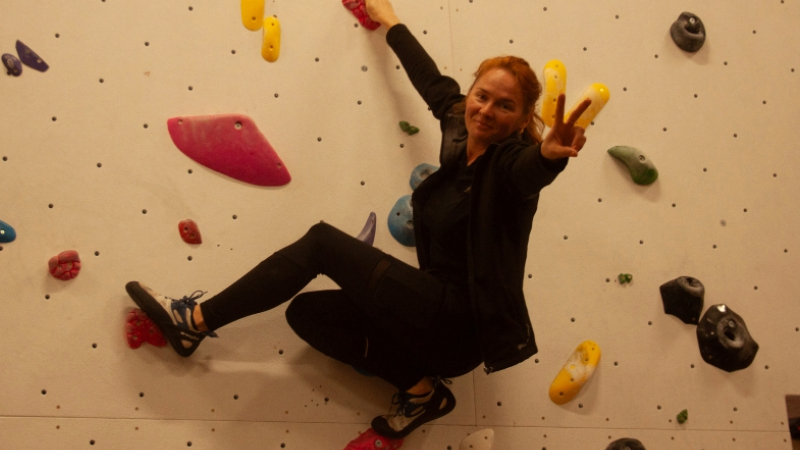 A woman showing the peace sign on a climbing wall