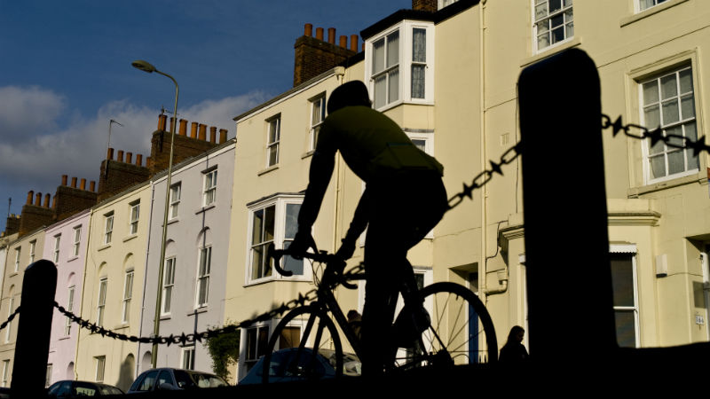 Cyclist silhouetted in front of houses