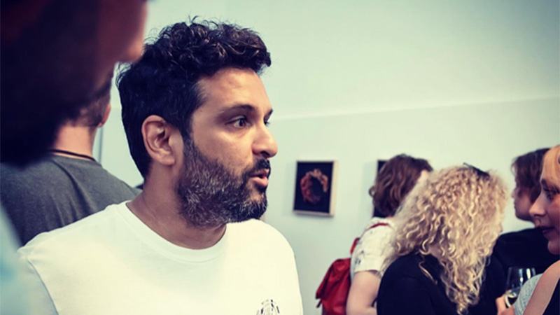 Image of artist Faisal Hussain, at an art exhibition with others in the background