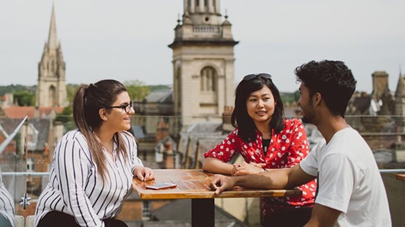 Three students talking on a rooftop in Oxford