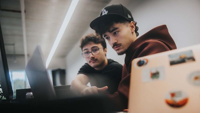 Side view of two students with their laptops