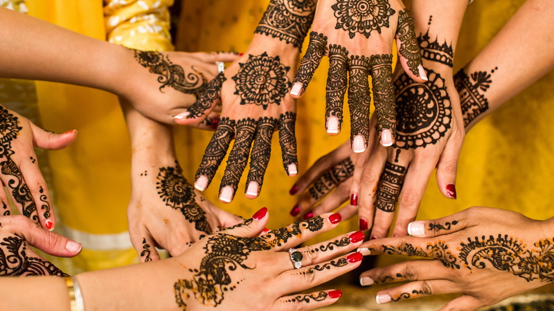 Many hands, all decorated with henna