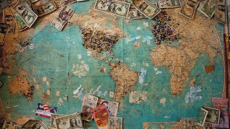 image of a world map with pins and money layed out on it